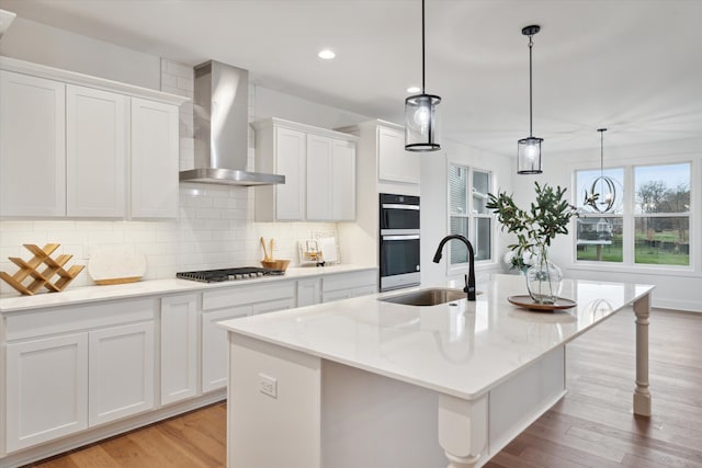 kitchen featuring a kitchen island with sink and wall chimney range hood