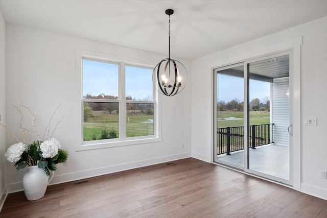 unfurnished dining area featuring wood-type flooring and a notable chandelier