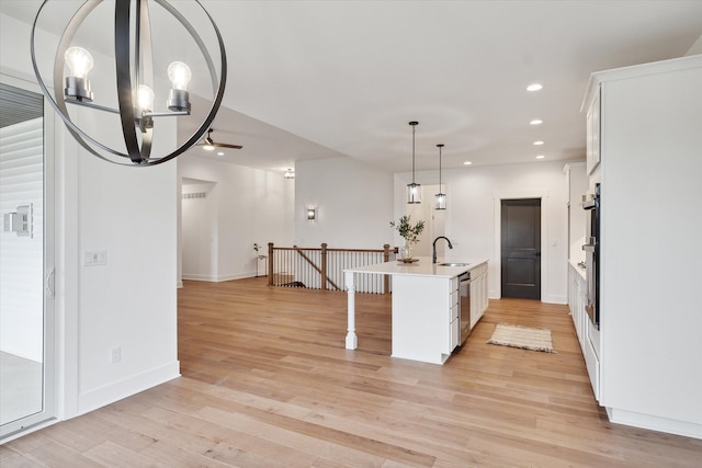 kitchen with pendant lighting, sink, a center island with sink, and white cabinets