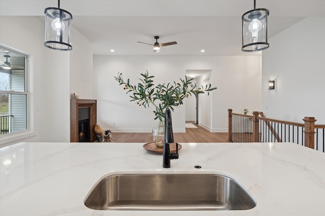 details with ceiling fan, sink, light stone counters, and decorative light fixtures