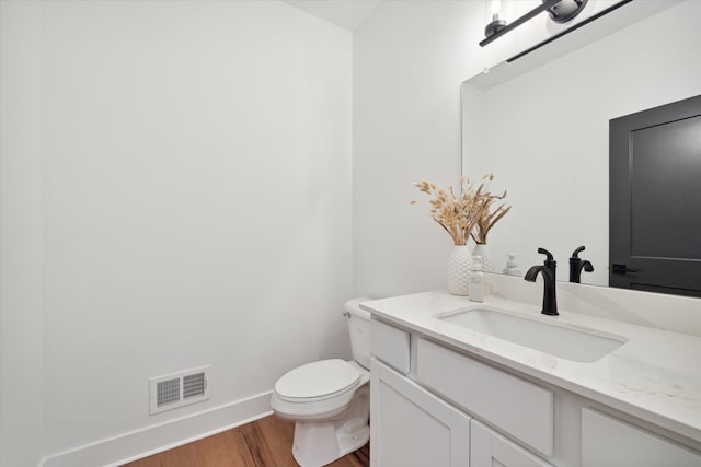 bathroom with hardwood / wood-style flooring, vanity, and toilet