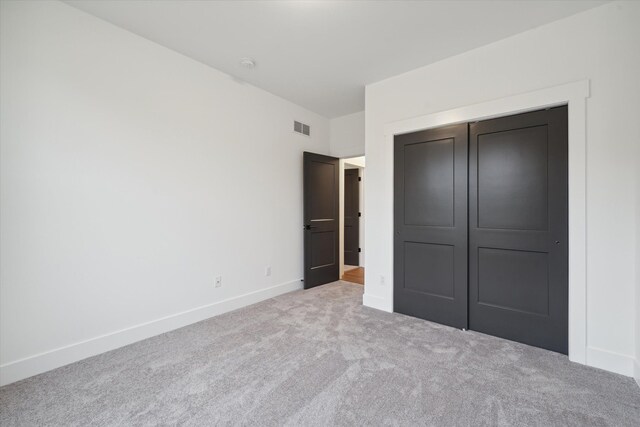 unfurnished bedroom featuring light carpet and a closet