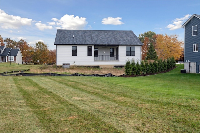 rear view of house featuring a porch, central air condition unit, and a lawn