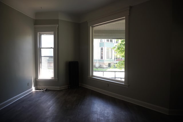 unfurnished room featuring dark hardwood / wood-style floors and radiator heating unit