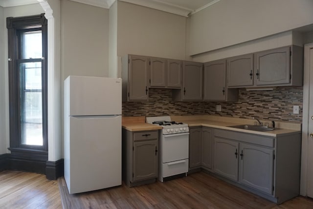 kitchen with hardwood / wood-style flooring, gray cabinets, decorative backsplash, white appliances, and sink