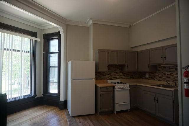 kitchen featuring white appliances, decorative backsplash, sink, light hardwood / wood-style floors, and crown molding