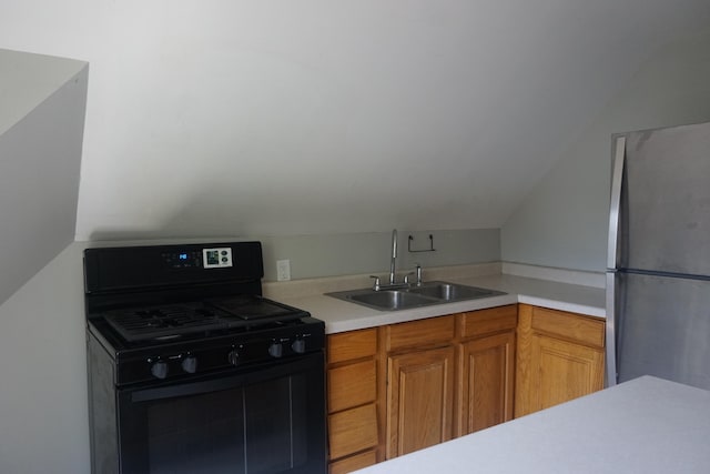 kitchen with black gas range, vaulted ceiling, stainless steel fridge, and sink