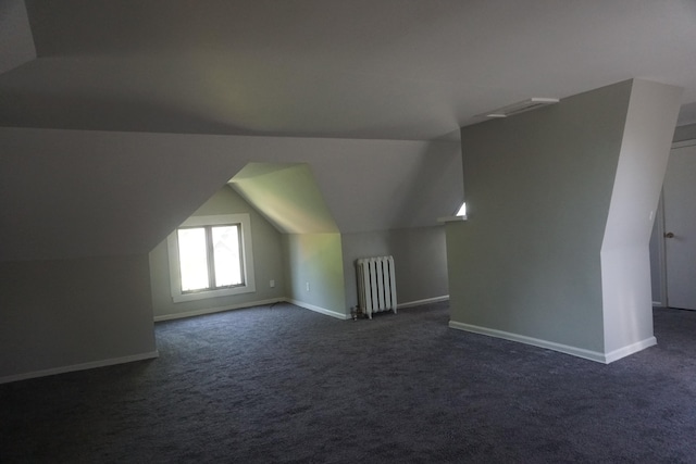 bonus room with dark carpet, radiator heating unit, and lofted ceiling