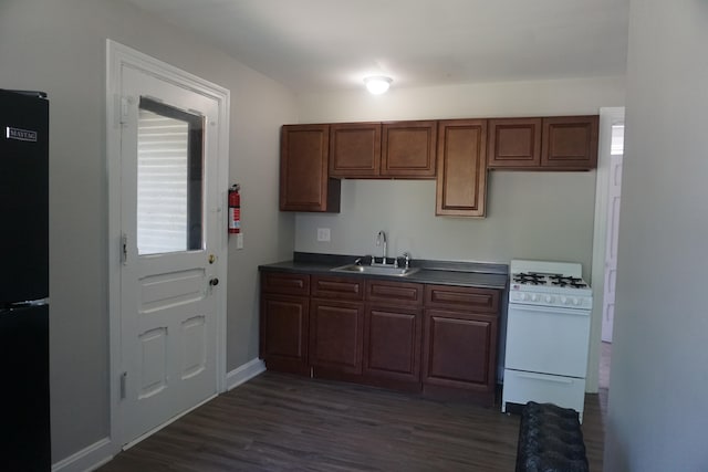 kitchen with black refrigerator, dark wood-type flooring, sink, and white range with gas cooktop