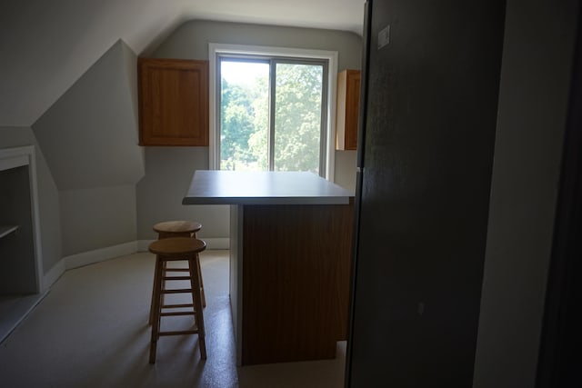 kitchen featuring a kitchen bar, light carpet, and lofted ceiling