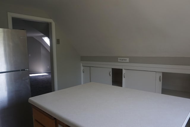 bedroom featuring lofted ceiling and stainless steel refrigerator