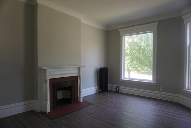 unfurnished living room featuring dark hardwood / wood-style floors and radiator heating unit