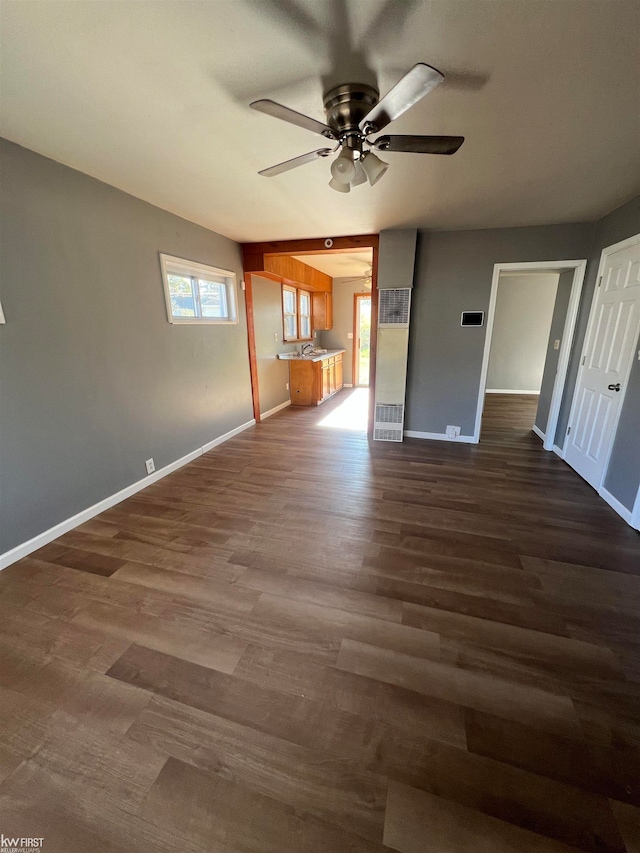 unfurnished living room featuring ceiling fan and dark wood-type flooring