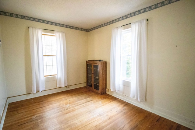 unfurnished room with a healthy amount of sunlight and wood-type flooring