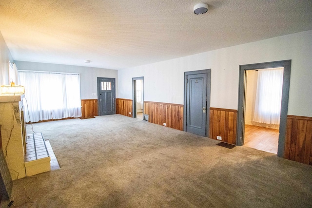 carpeted spare room featuring wooden walls and a textured ceiling