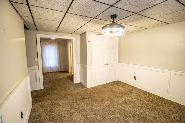 spare room with dark colored carpet and a paneled ceiling