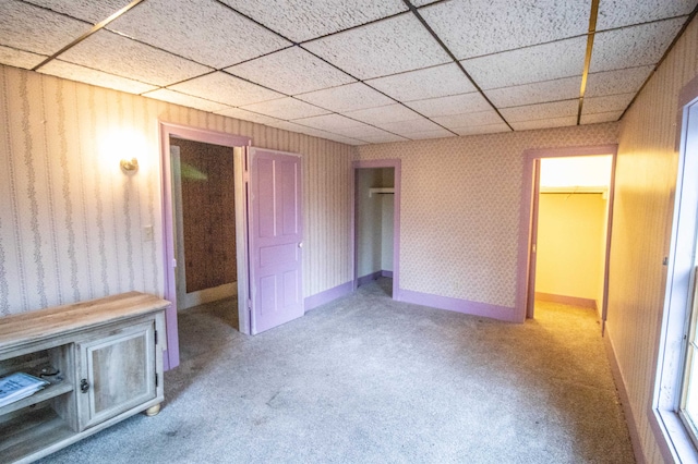 unfurnished bedroom featuring a drop ceiling, light colored carpet, and a closet