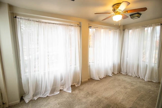 unfurnished room with ceiling fan, light colored carpet, and a wealth of natural light