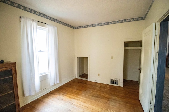 unfurnished bedroom featuring hardwood / wood-style floors and a closet