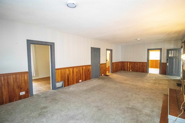 carpeted empty room featuring wood walls