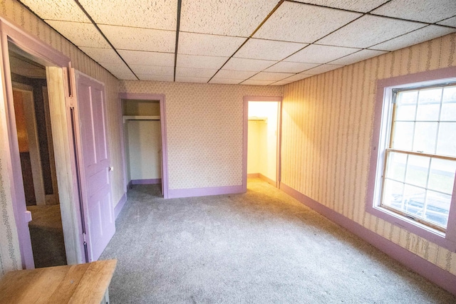 unfurnished bedroom featuring a paneled ceiling, carpet floors, and a closet