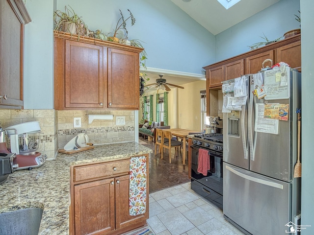 kitchen with stainless steel refrigerator with ice dispenser, backsplash, gas stove, ceiling fan, and high vaulted ceiling