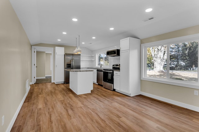 kitchen featuring hanging light fixtures, a kitchen island, stainless steel appliances, and lofted ceiling