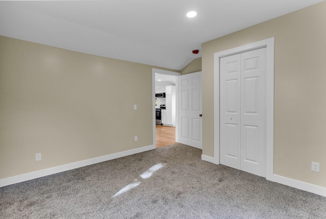 unfurnished room featuring light colored carpet and lofted ceiling