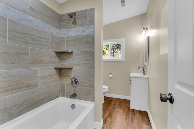 full bathroom featuring vanity, wood-type flooring, tiled shower / bath combo, and toilet