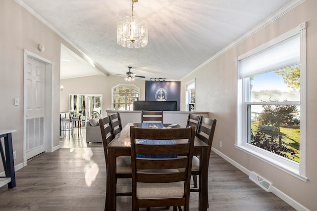 dining area featuring ceiling fan with notable chandelier, a textured ceiling, crown molding, wood-type flooring, and lofted ceiling with beams