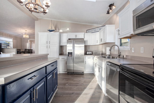 kitchen with blue cabinets, a notable chandelier, vaulted ceiling, white cabinets, and appliances with stainless steel finishes