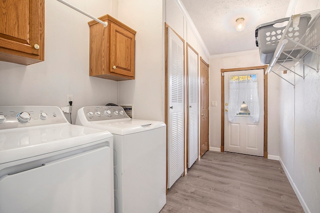 clothes washing area with washer and clothes dryer, light hardwood / wood-style floors, cabinets, and crown molding