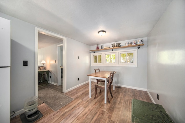 dining area with wood-type flooring and a textured ceiling