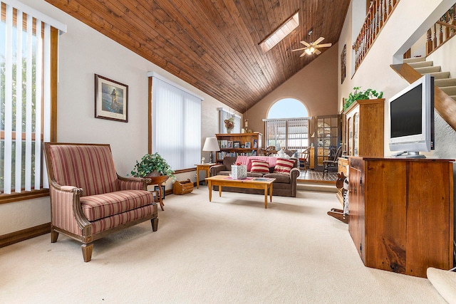 living area with ceiling fan, wood ceiling, light carpet, and a skylight