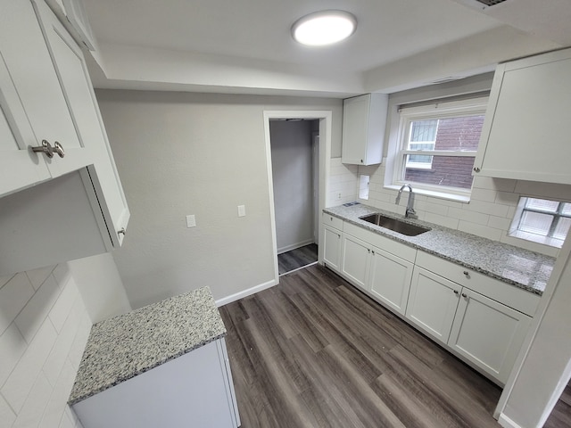 kitchen featuring light stone countertops, dark hardwood / wood-style floors, white cabinetry, and sink