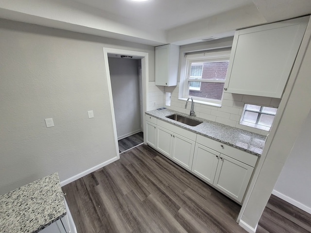 kitchen featuring backsplash, light stone counters, sink, and white cabinets