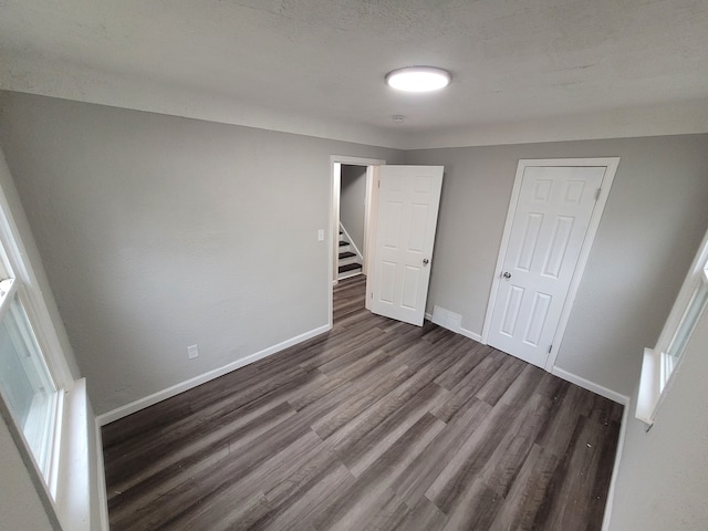 unfurnished bedroom with a closet and dark wood-type flooring