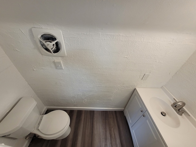 bathroom with wood-type flooring, vanity, a textured ceiling, and toilet