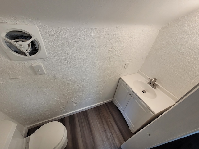 bathroom featuring toilet, vanity, hardwood / wood-style flooring, and vaulted ceiling