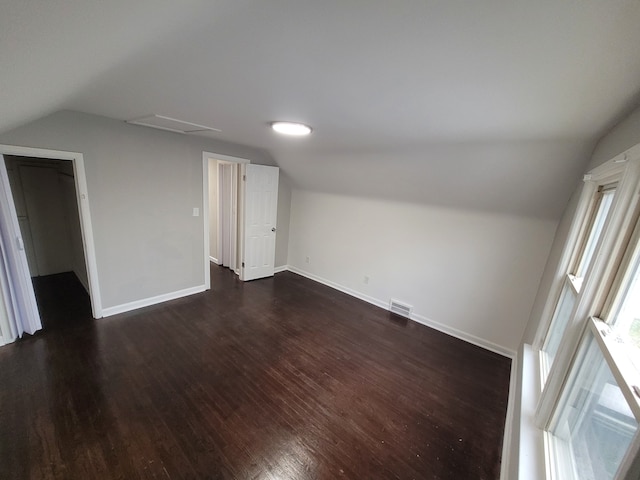 spare room featuring vaulted ceiling and dark wood-type flooring