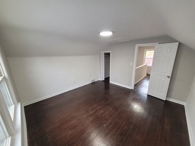 additional living space with dark wood-type flooring and vaulted ceiling