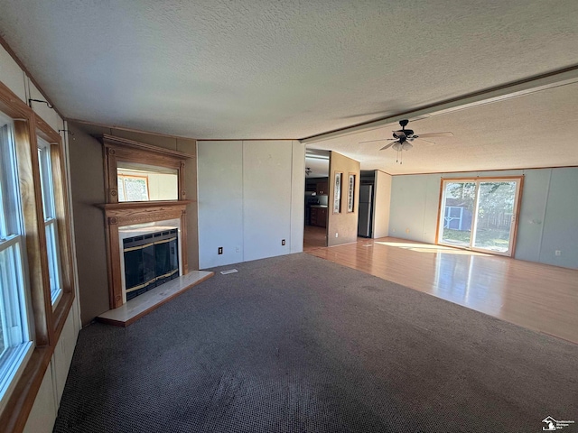 unfurnished living room featuring hardwood / wood-style flooring, ceiling fan, and a textured ceiling