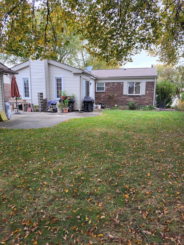 rear view of property featuring a lawn and a patio