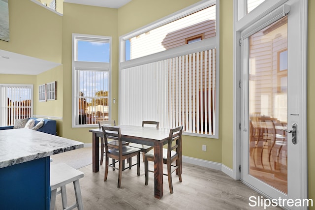 dining area featuring light hardwood / wood-style flooring and a high ceiling