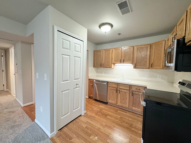 kitchen featuring backsplash, light wood-type flooring, sink, and appliances with stainless steel finishes