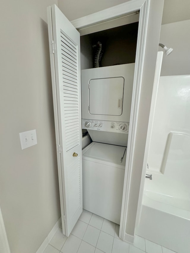 laundry area featuring light tile patterned floors and stacked washing maching and dryer