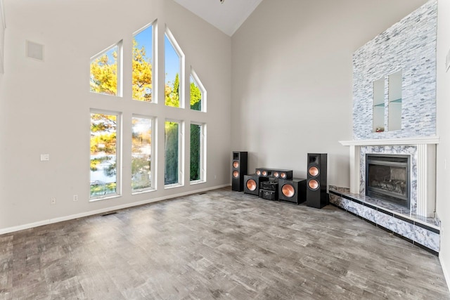 unfurnished living room with hardwood / wood-style floors, high vaulted ceiling, and a healthy amount of sunlight