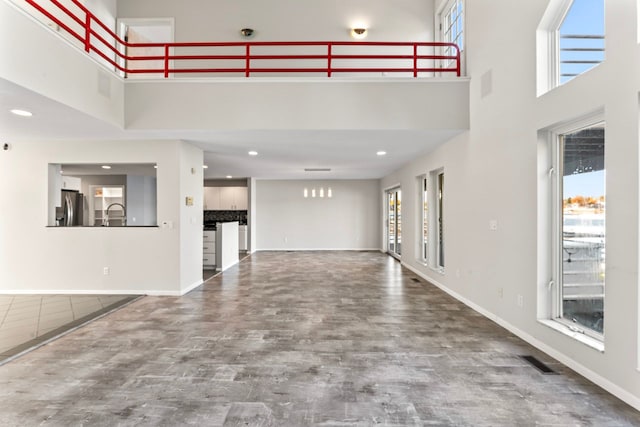 unfurnished living room featuring a high ceiling, plenty of natural light, and hardwood / wood-style floors