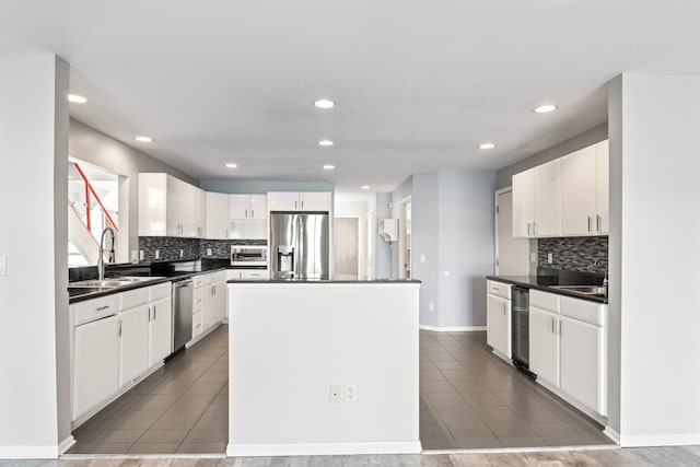 kitchen with appliances with stainless steel finishes, tasteful backsplash, sink, a center island, and white cabinetry