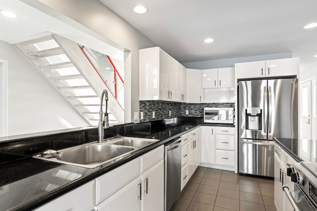 kitchen featuring backsplash, white cabinets, sink, dark tile patterned floors, and appliances with stainless steel finishes